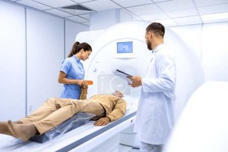 Experienced radiologists encouraging senior patient before MRI or CT scanning procedure in hospital.