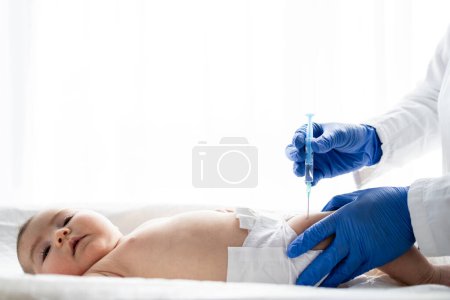 Photo for Pediatrician or nurse giving an intramuscular injection of a vaccine to the leg of baby girl. Immunization for children concept. - Royalty Free Image