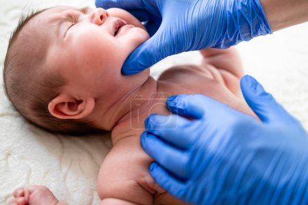 Médecin vérifiant le cou du bébé pour des éruptions cutanées et irritation de la peau.