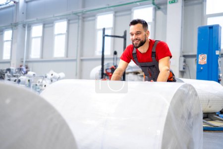 Téléchargez les photos : Travailler dans une usine de cellulose poussant des rouleaux de nouveau papier. - en image libre de droit