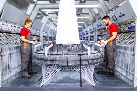 Trabajadores que controlan la máquina textil para la producción de bolsas industriales.