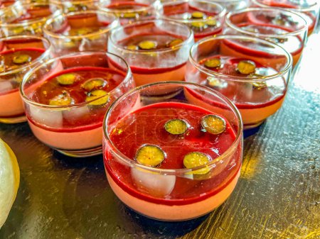 Photo for Panna cotta in milk with strawberry or raspberry sauce. Delicate Italian dessert, topped with natural jelly, decorated with halves of grapes. at catering event on some festive event, party or wedding - Royalty Free Image