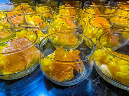 Téléchargez les photos : Exotic mousse, served with diced mango, garnished with caramelized sugar in a glass bowl. at catering event on some festive event, party or wedding reception. buffet. - en image libre de droit