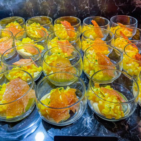 Téléchargez les photos : Exotic mousse, served with diced mango, garnished with caramelized sugar in a glass bowl. at catering event on some festive event, party or wedding reception. buffet. - en image libre de droit