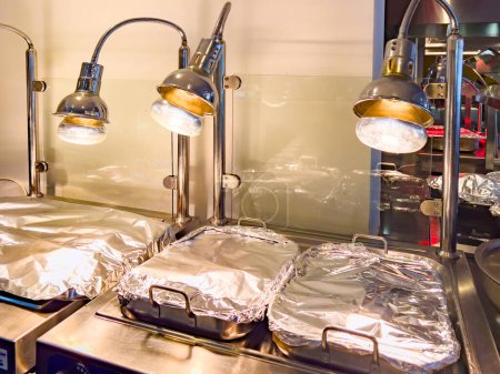 Photo for Professional Heating Equipment, Food and dish warmer, with large trays covered with foil. ideal for short-term warming up of served hot dishes, ready-made pizza, any other ready-made hot products. - Royalty Free Image