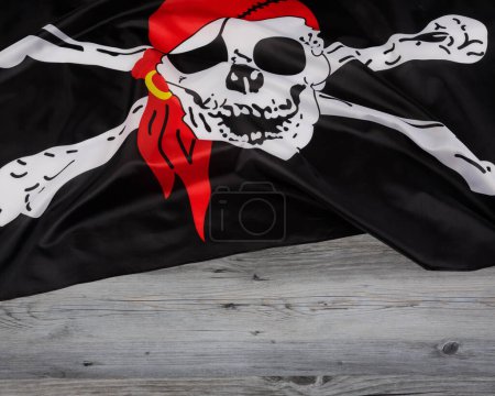Téléchargez les photos : Crâne et os croisés des pirates noirs Drapeau aka le Jolly Roger avec un fond en bois et un espace de copie - en image libre de droit