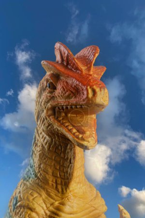 Téléchargez les photos : Jouet Allosaurus dinosuar qui a vécu pendant la période jurassique isolé sur un fond de ciel avec espace de copie - en image libre de droit
