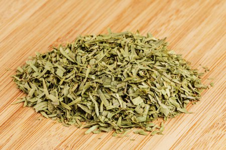 Photo for A pile of dried Tarragon Leaves isolated on a wooden cutting board with copy space - Royalty Free Image