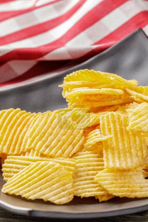 Photo for A black plate with Cheddar and Sour Cream Potatoe chips make a great snack - Royalty Free Image