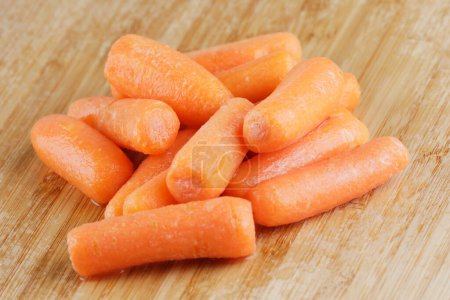 Photo for Close up of a pile of delicious Baby Carrots on wooden cutting board with copy space - Royalty Free Image