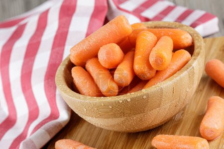 Foto de Primer plano de un cuenco de madera lleno de deliciosas zanahorias bebé con espacio para copiar - Imagen libre de derechos