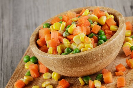 Photo for Close up of a wooden bowl of delicious mixed vegetables including carrots, peas, and sweet corn with copy space - Royalty Free Image