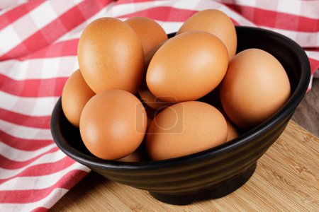 Photo for Close up of a bowl of fresh raw Brown Eggs with a wooden background and copy space - Royalty Free Image