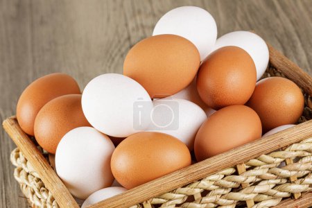 Téléchargez les photos : Gros plan d'un panier d'œufs blancs et bruns crus frais avec espace de copie - en image libre de droit