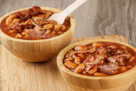 Photo for A wooden bowl of Baked Beans also known as Pork & Beans on a wooden background with copy space - Royalty Free Image