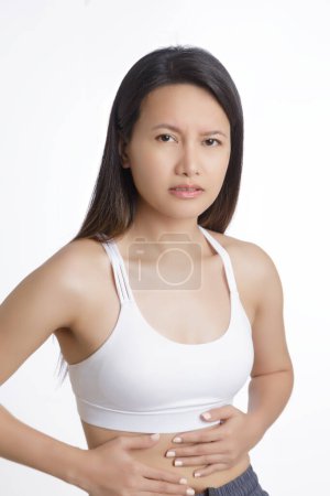 Foto de Mujer asiática que sufre de un dolor de estómago aislado sobre un fondo blanco con espacio de copia - Imagen libre de derechos