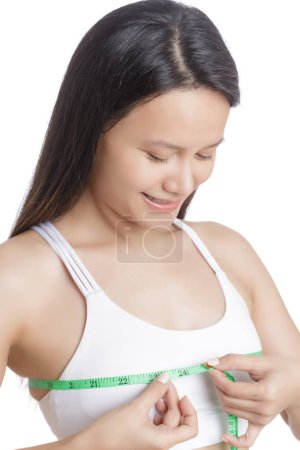 Foto de Hermosa joven asiática que mide su pecho aislado sobre un fondo blanco con espacio para copiar - Imagen libre de derechos