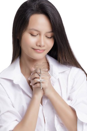 Téléchargez les photos : Jeune catholique asiatique américain priant sur un fond blanc avec espace de copie - en image libre de droit