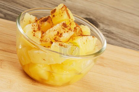 Photo for A close up of delicious Pineapple Chunks and Cinnamon Power in juicy Syrup on a wooden background with copy space - Royalty Free Image