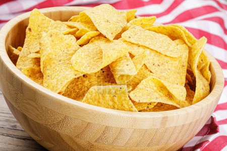 Photo for A large wooden bowl of delicious Roasted Corn Tortilla or Nacho Chips on a wooden background with copy space - Royalty Free Image
