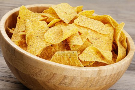 Photo for A large wooden bowl of delicious Roasted Corn Tortilla or Nacho Chips on a wooden background with copy space - Royalty Free Image
