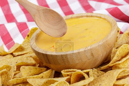 Foto de Un gran tazón de madera de deliciosa salsa de queso y tortilla de maíz tostado o chips de Nacho sobre un fondo de madera con espacio para copiar - Imagen libre de derechos