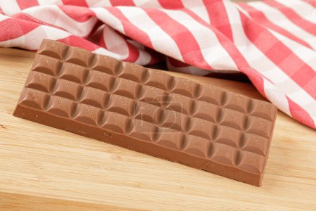 Foto de Primer plano de una deliciosa barra de chocolate con leche aislada sobre un fondo de madera con espacio para copiar - Imagen libre de derechos