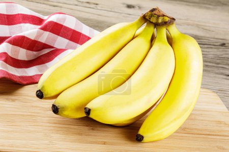 Foto de Primer plano de un ramo de deliciosos plátanos maduros aislados sobre un fondo de madera con espacio para copiar - Imagen libre de derechos