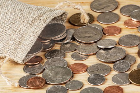 Monedas americanas saliendo de una bolsa de arpillera en la parte superior de la mesa con espacio para copiar