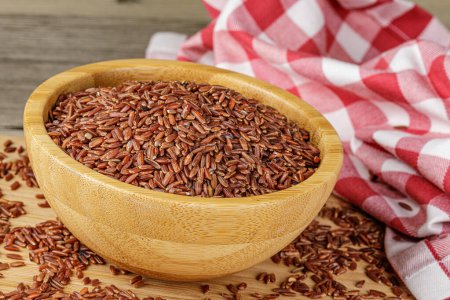 A Wooden Bowl of delicious and healthy Red Rice isolated on a wooden background with copy space