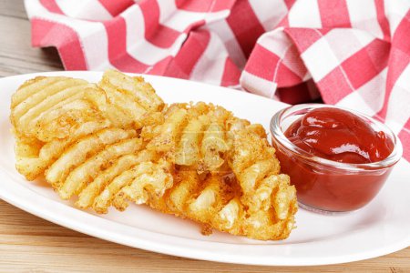 Photo for Delicious Waffle Fries isolated on a wooden background with Ketchup and copy space - Royalty Free Image