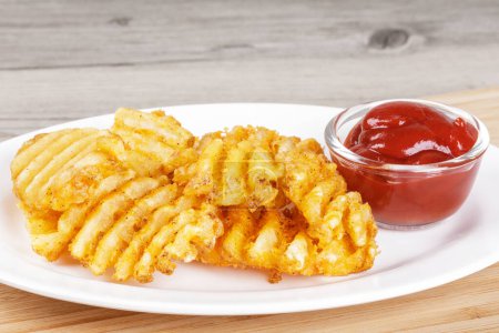 Photo for Delicious Waffle Fries isolated on a wooden background with Ketchup and copy space - Royalty Free Image
