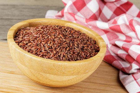 Photo for A Wooden Bowl of delicious and healthy Red Rice isolated on a wooden background with copy space - Royalty Free Image