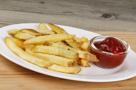 Téléchargez les photos : Une assiette de délicieux Skin On French Fries sur un fond en bois avec Ketchup et espace de copie - en image libre de droit