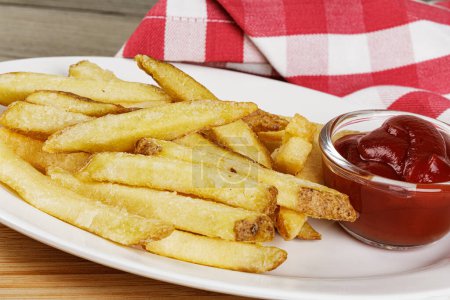 Photo for A plate of delicious Skin On French Fries on a wooden background with Ketchup and copy space - Royalty Free Image