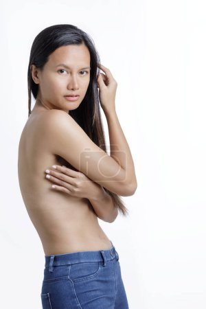 Foto de Joven mujer asiática posando en topless usando las manos para cubrir el pecho aislado sobre un fondo blanco con espacio para copiar - Imagen libre de derechos