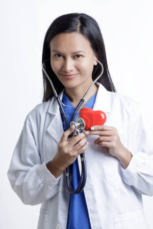 Photo for Asian American Woman Doctor examining a Red Heart concept 0f Love of health care isolated on a white background with copy space - Royalty Free Image