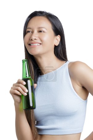 Foto de Hermoso asiático americano celebrando mientras sostiene una botella de deliciosa cerveza aislada sobre un fondo blanco con espacio para copiar - Imagen libre de derechos