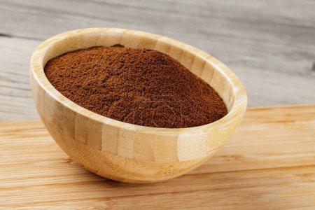 Photo for Close up of a wooden bowl of Fresh Ground Coffee isolated on a wooden background with copy space - Royalty Free Image