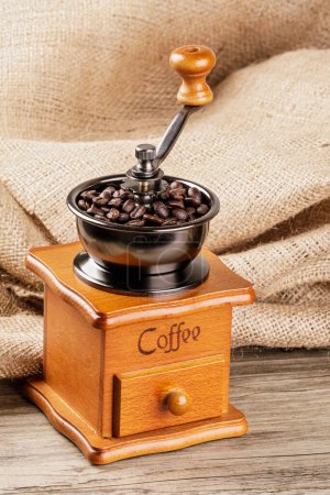 Téléchargez les photos : Un moulin à café vintage isolé sur une table en bois avec un fond en toile de jute et un espace de copie - en image libre de droit