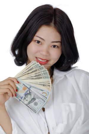 Téléchargez les photos : Une belle femme sino-américaine tenant des billets de banque des États-Unis isolés sur fond blanc avec espace de copie - en image libre de droit