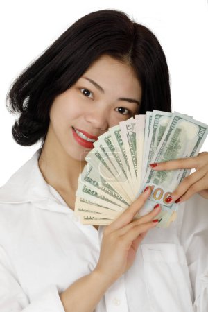 Téléchargez les photos : Une belle femme sino-américaine tenant des billets de banque des États-Unis isolés sur fond blanc avec espace de copie - en image libre de droit