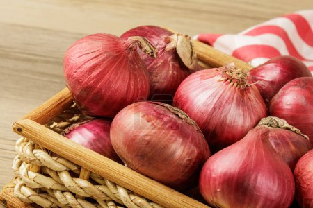 Photo for Close up of a basket of Red Onions on a wooden background with copy space - Royalty Free Image