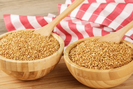 Photo for Close up of a wooden bowl filled with healthy and delicious Roasted Flax Seeds isolated on a wooden background with copy space - Royalty Free Image