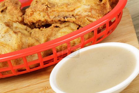 Photo for Red basket of delicious Drumsticks and Thighs of Fried Chicken  and Gravy with copy space - Royalty Free Image