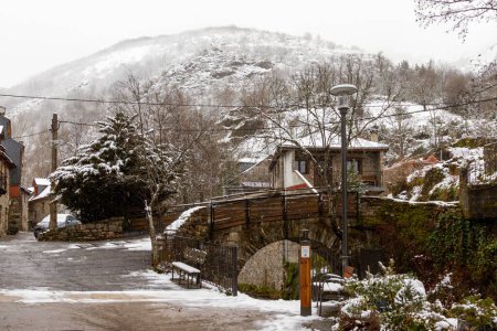 Foto de Un puente de piedra sobre un río en una ciudad montañosa nevada - Imagen libre de derechos
