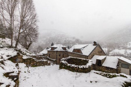 an old stone barn in a pretty snowy mountain village