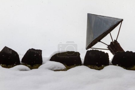 Metallschornstein auf einem schneebedeckten Schieferdach
