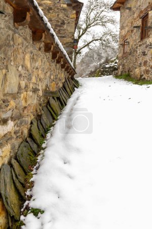row of slate tiles stacked on the wall of a stone farmhouse in a snowy mountain village