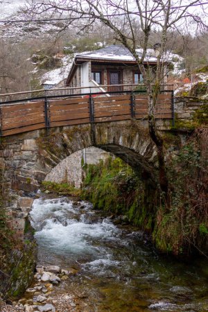 a stone bridge over a river in a snowy mountain town